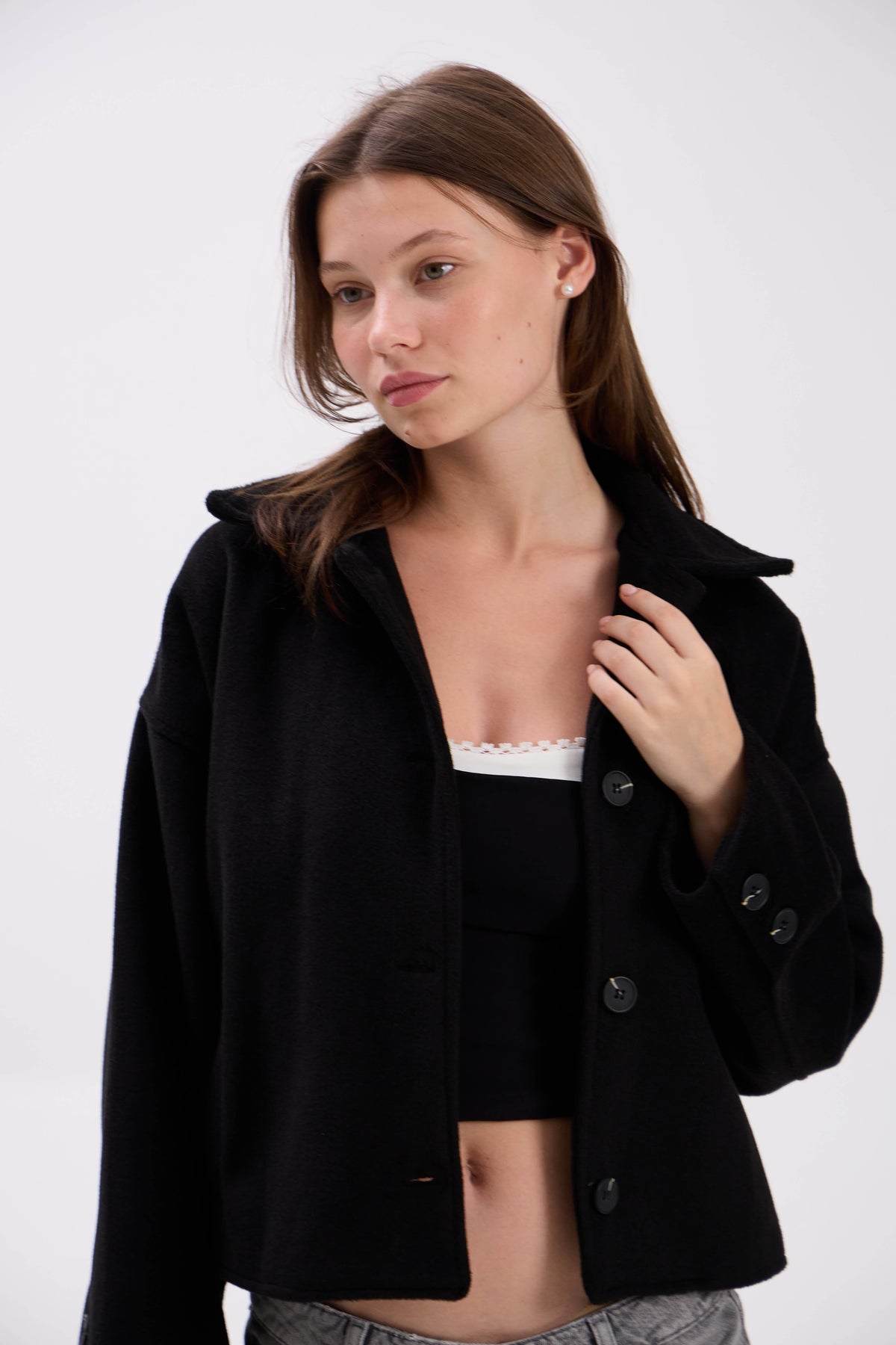 Woman wearing a black jacket over a white top on a white background