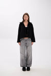 Person wearing a black jacket and gray jeans on a white background