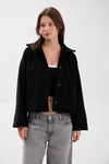 Woman wearing a black jacket and gray jeans on a white background