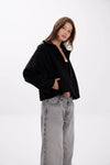 Person wearing a black jacket and gray jeans on a white background