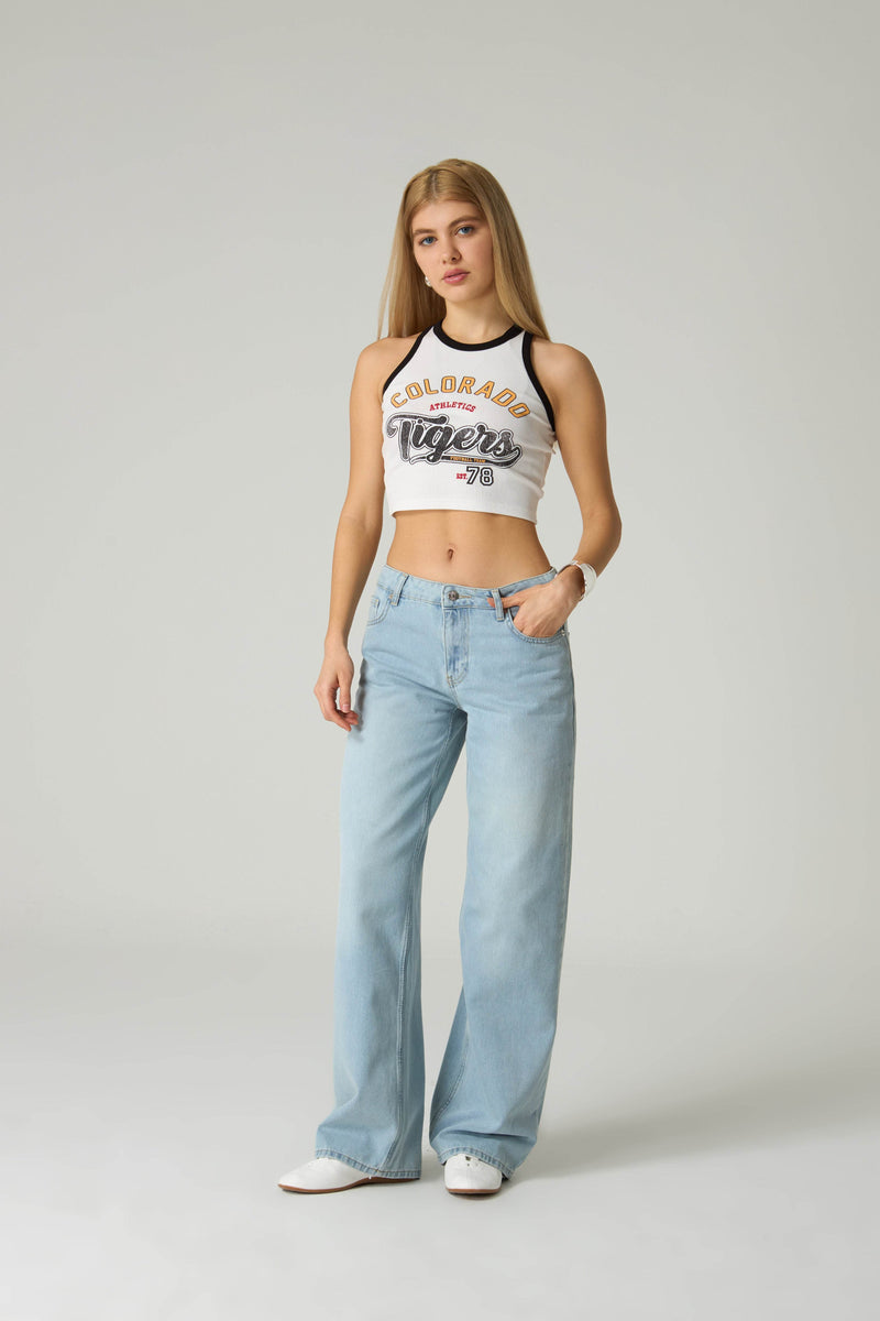 Woman wearing a white tank top with 'Colorado Tigers' text and light blue jeans on a plain background.