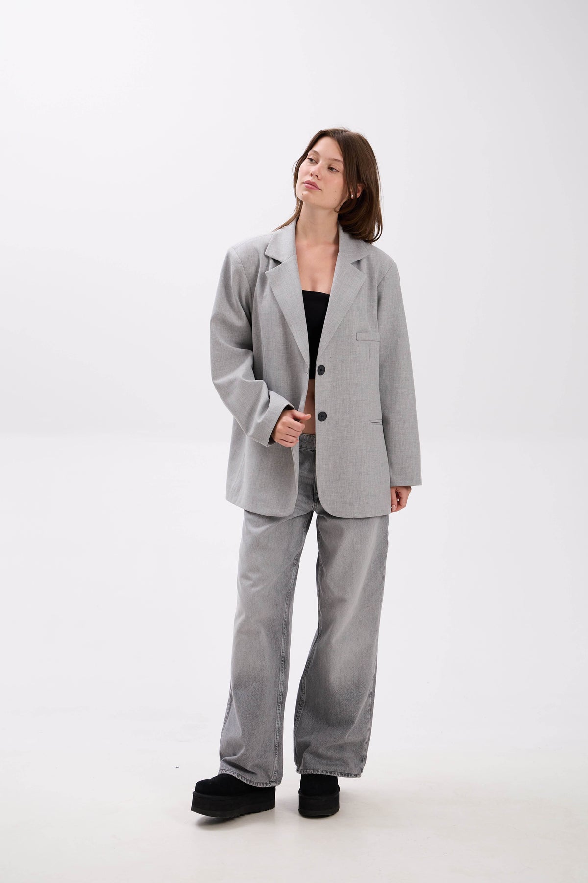 Woman wearing a gray suit on a white background.