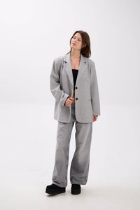 Woman wearing a gray suit on a white background.