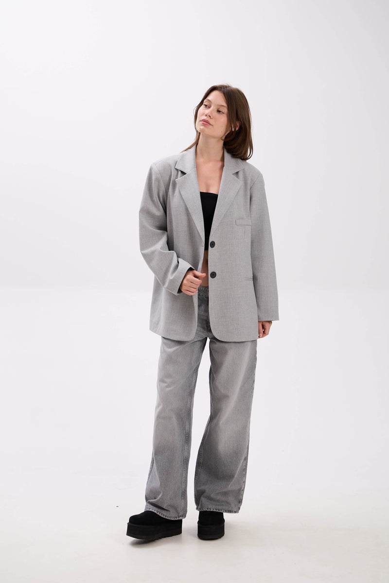 Woman wearing a gray suit on a white background.