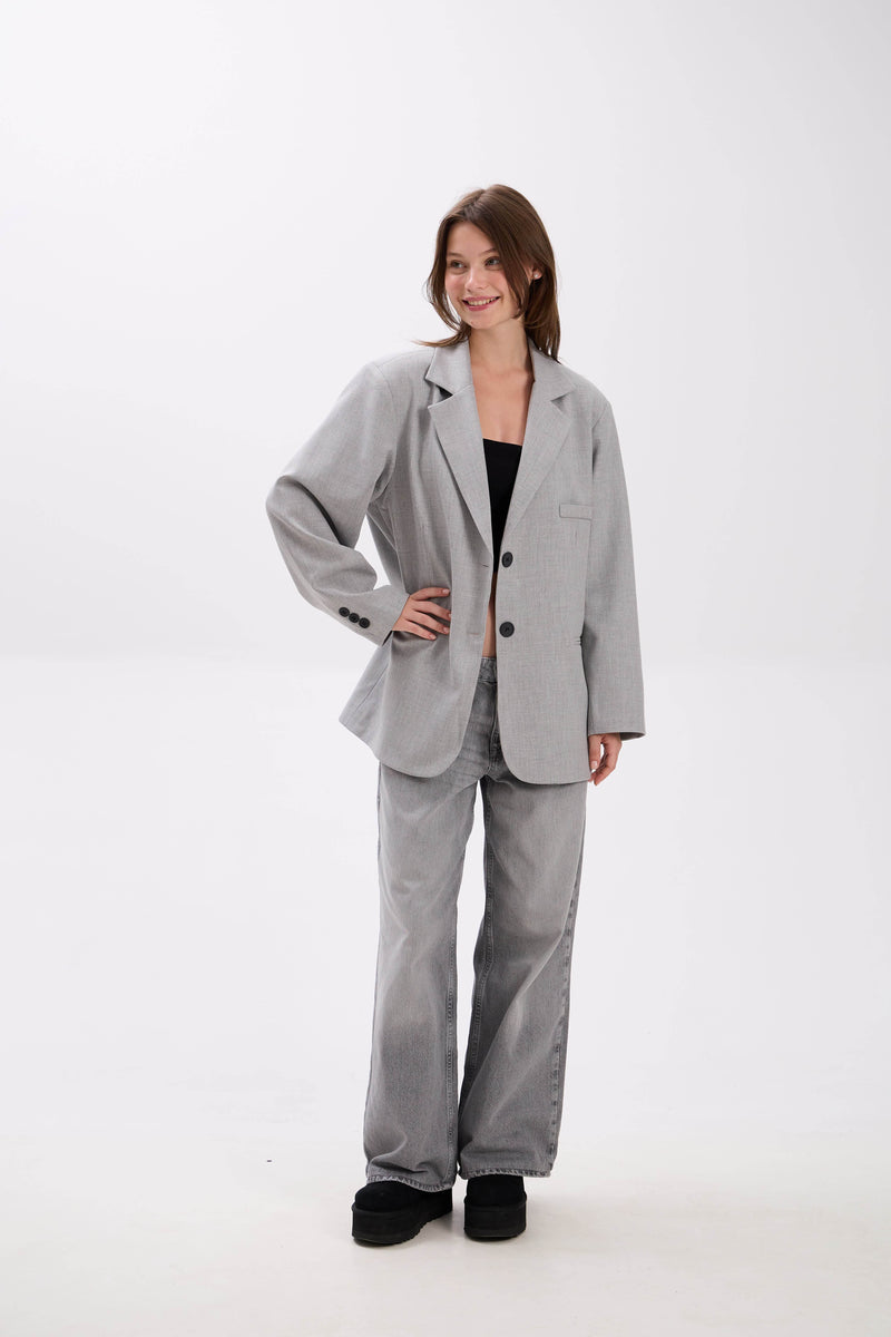 Woman wearing a gray suit on a white background.