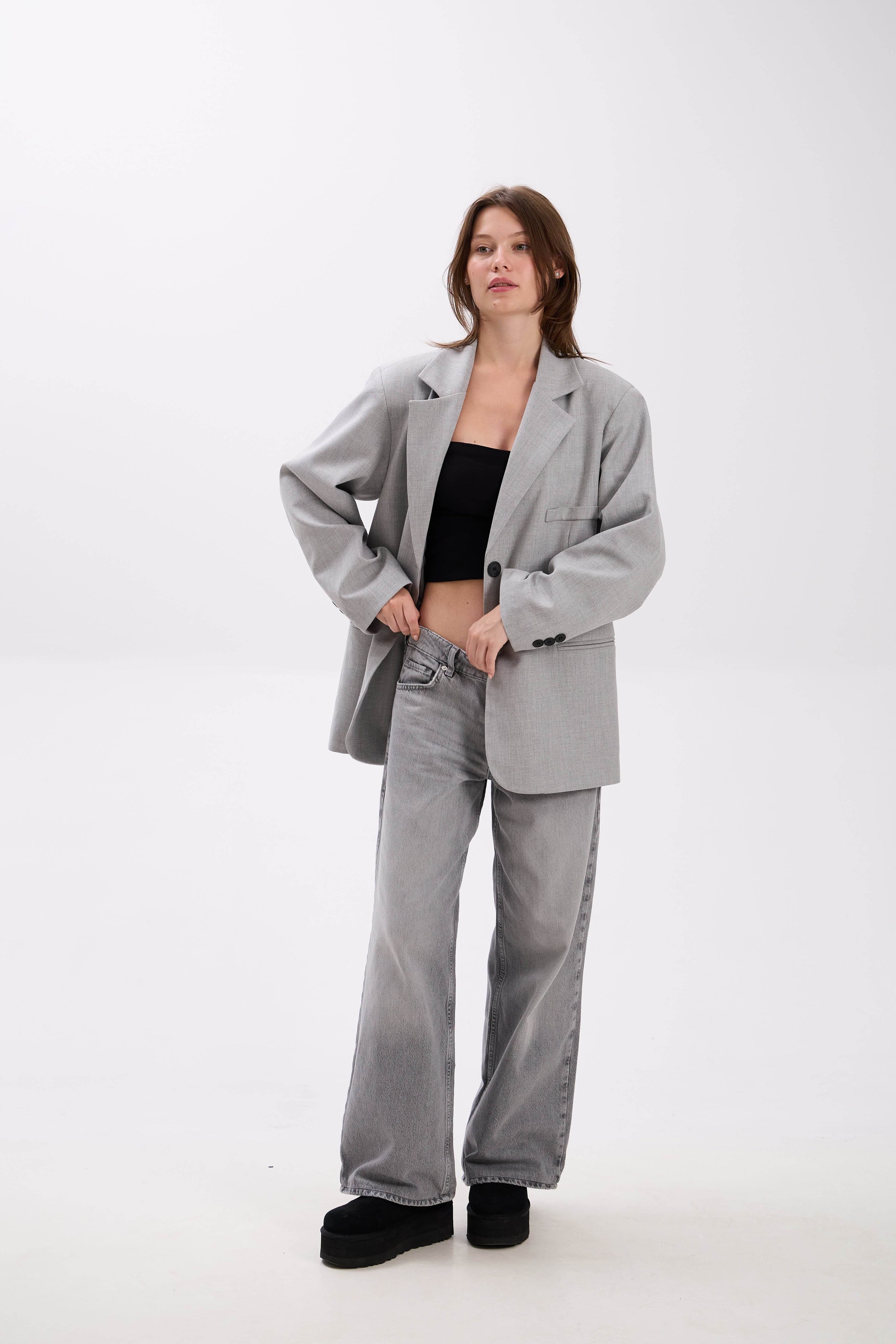 Person wearing a gray suit with a black top on a white background.