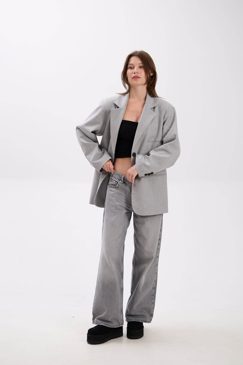 Person wearing a gray suit with a black top on a white background.