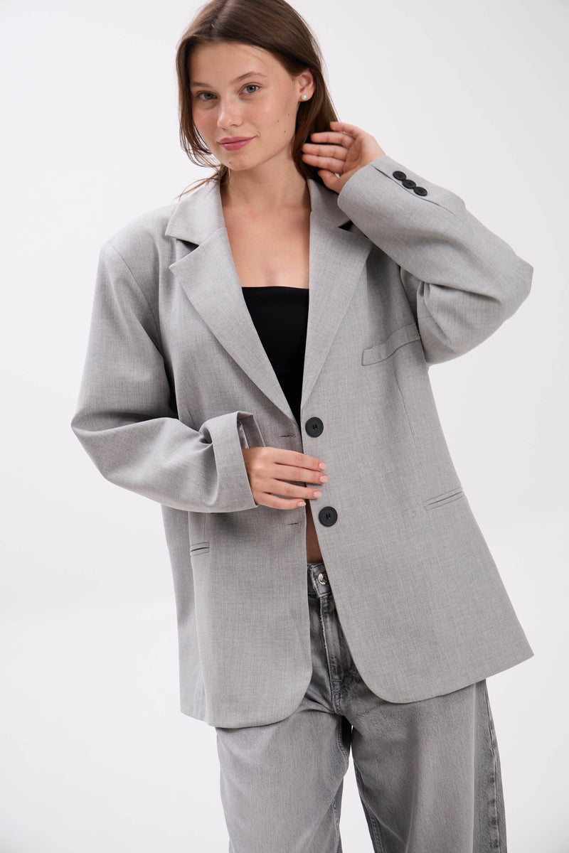 Woman wearing a gray suit on a white background.