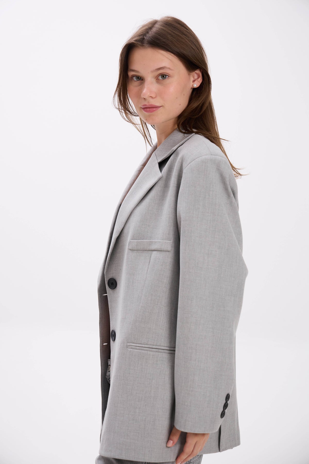 Woman wearing a gray blazer on a white background.
