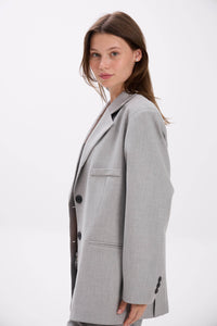 Woman wearing a gray blazer on a white background.