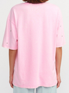 Person wearing a pink oversized t-shirt on a white background.