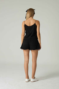 Person wearing a black romper with a plain background.
