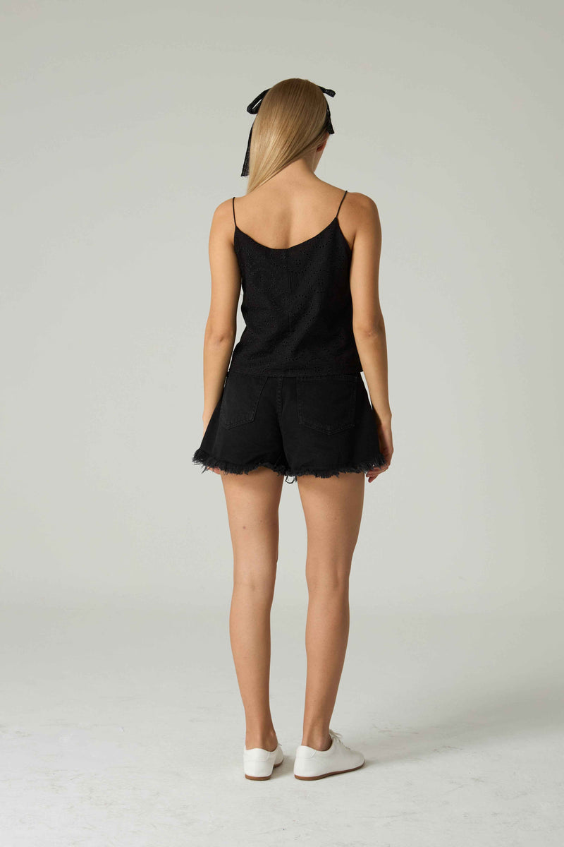 Person wearing a black romper with a plain background.