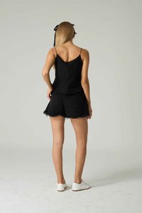 Person wearing a black lace-trimmed romper on a plain background.