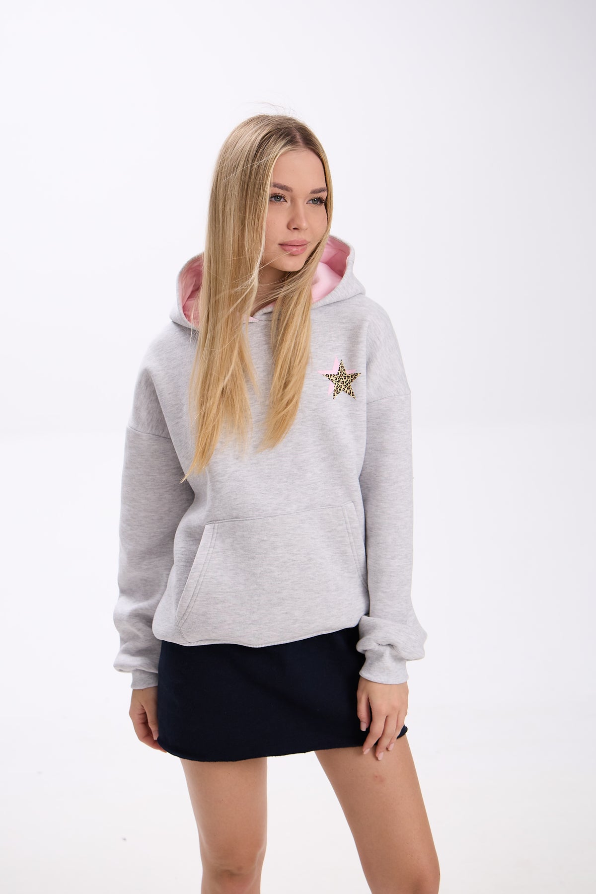 Woman wearing a gray hoodie with a pink hood and star design on a white background