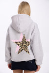 Person wearing a gray hoodie with a leopard print star on the back against a white background