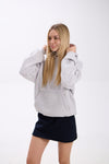 Woman wearing a gray hoodie and navy skirt on a white background