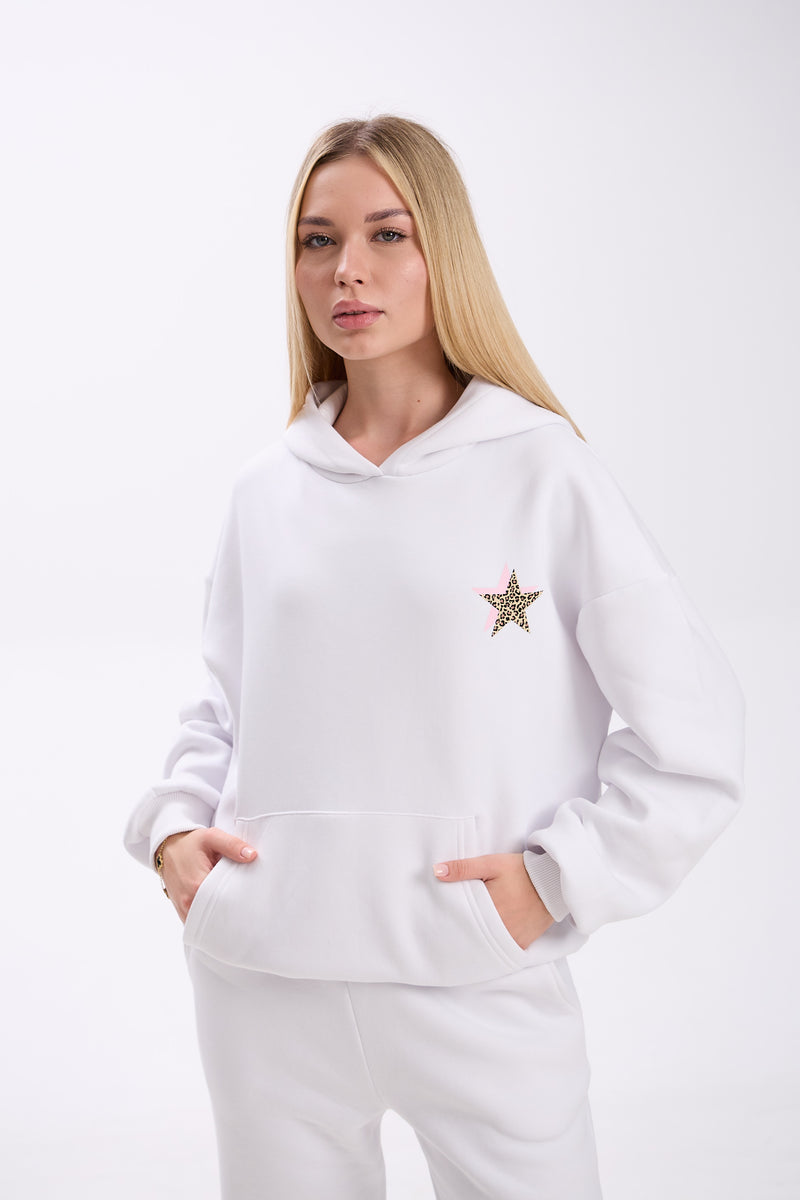 Woman wearing a white hoodie with a star design on a plain background