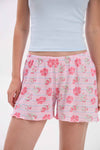 Person wearing a light blue crop top and pink floral shorts on a white .background
