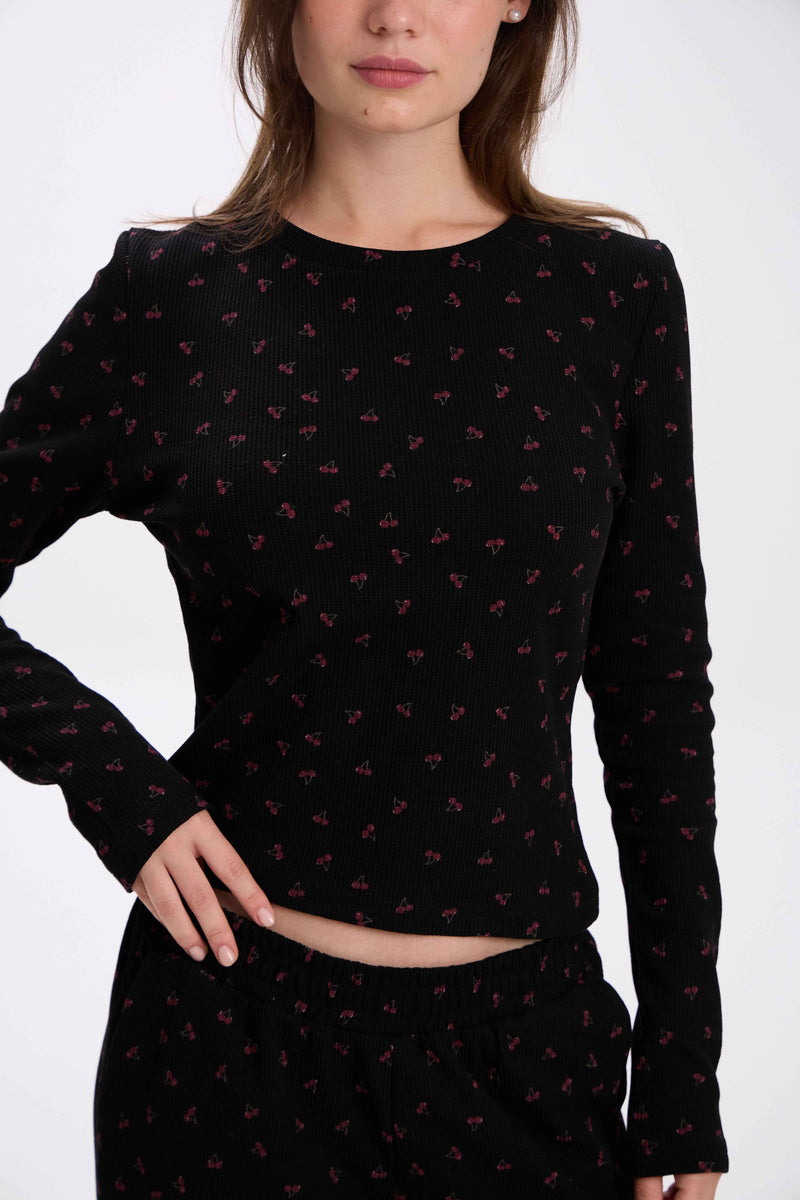 Black long-sleeve top with pink pattern worn by a model on a white background.