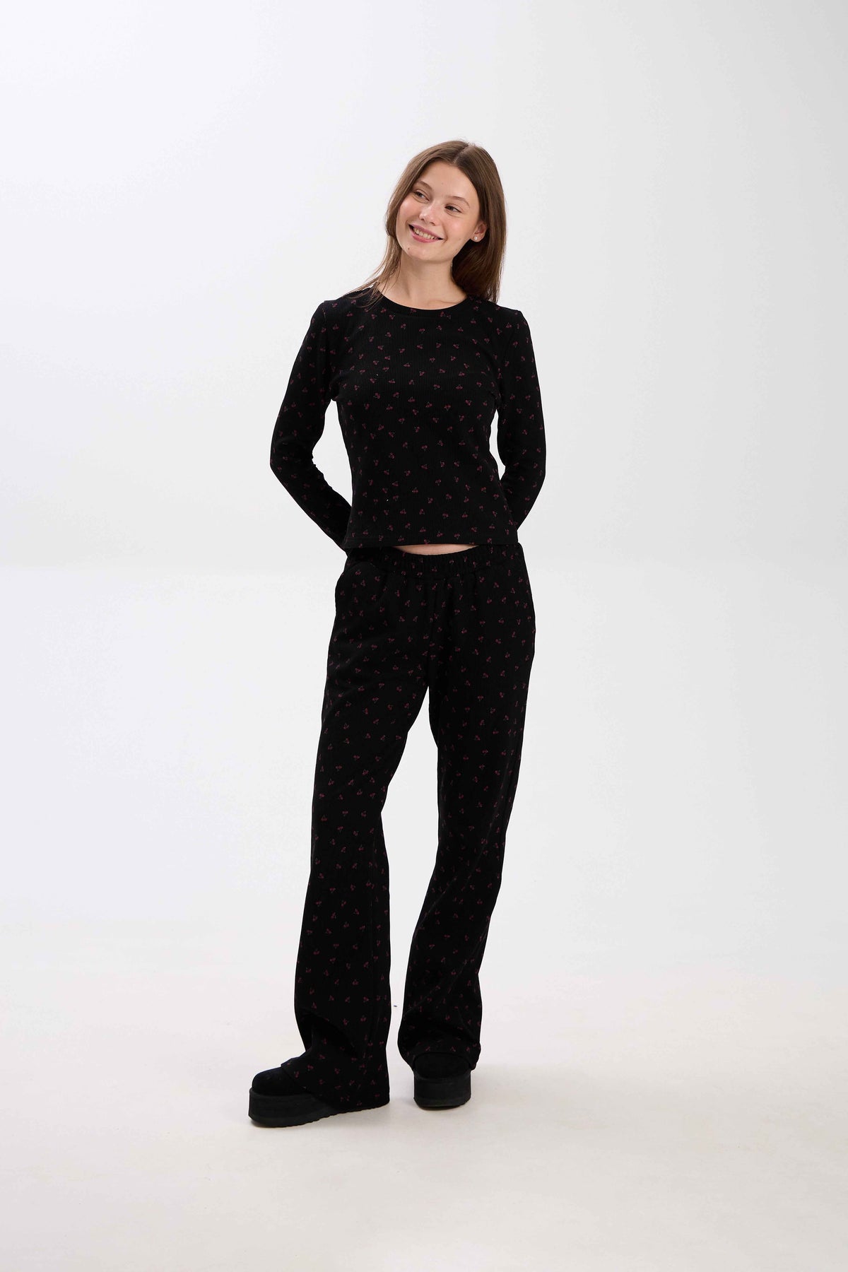 Woman wearing a black outfit with pink patterns on a white background.