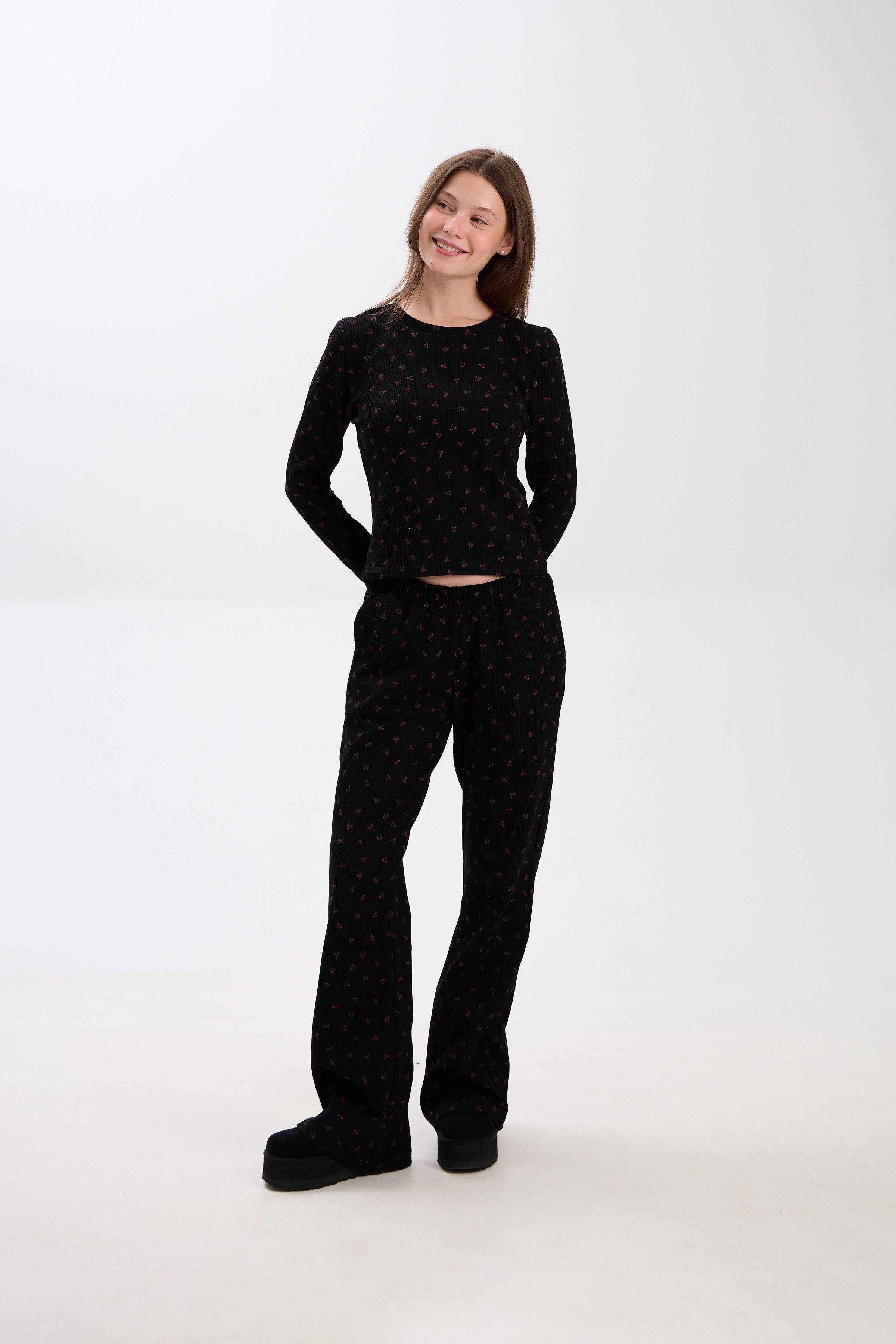 Woman wearing a black outfit with pink patterns on a white background.