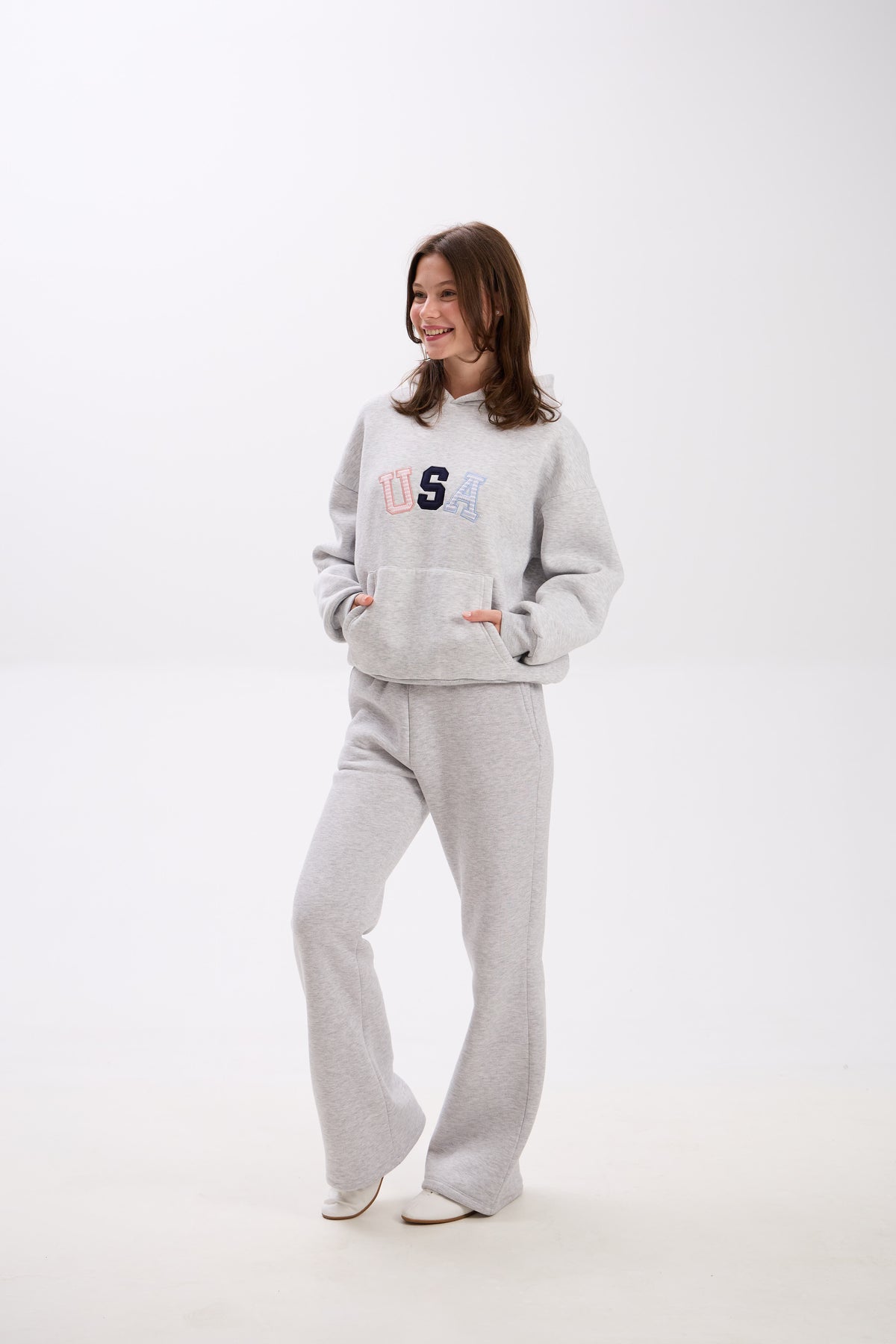 Woman wearing a gray sweatshirt and pants with 'USA' text on a white background.