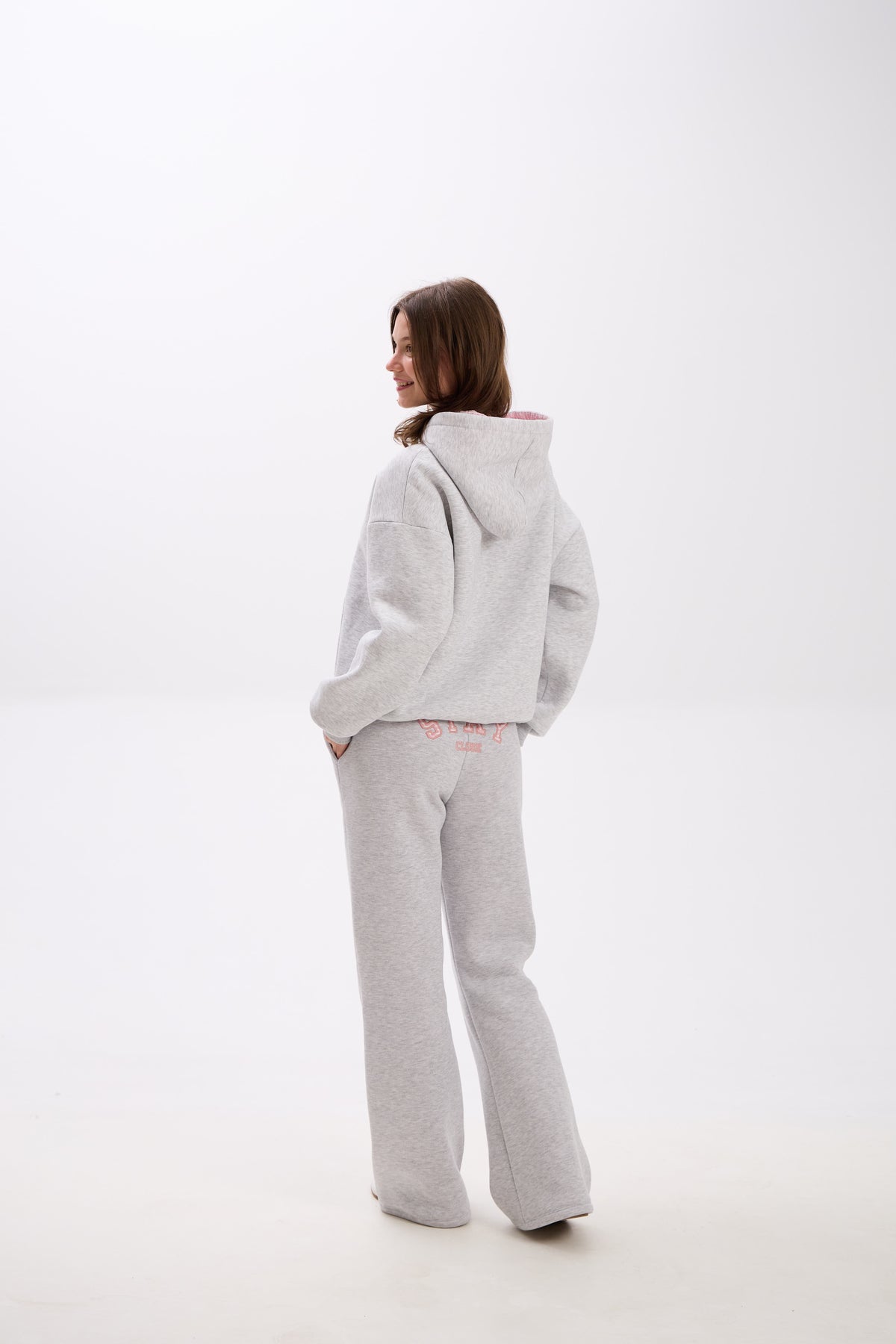 Grey sweatpants with elastic waistband, side pockets, and pink “Stay Close” embroidery on the back.