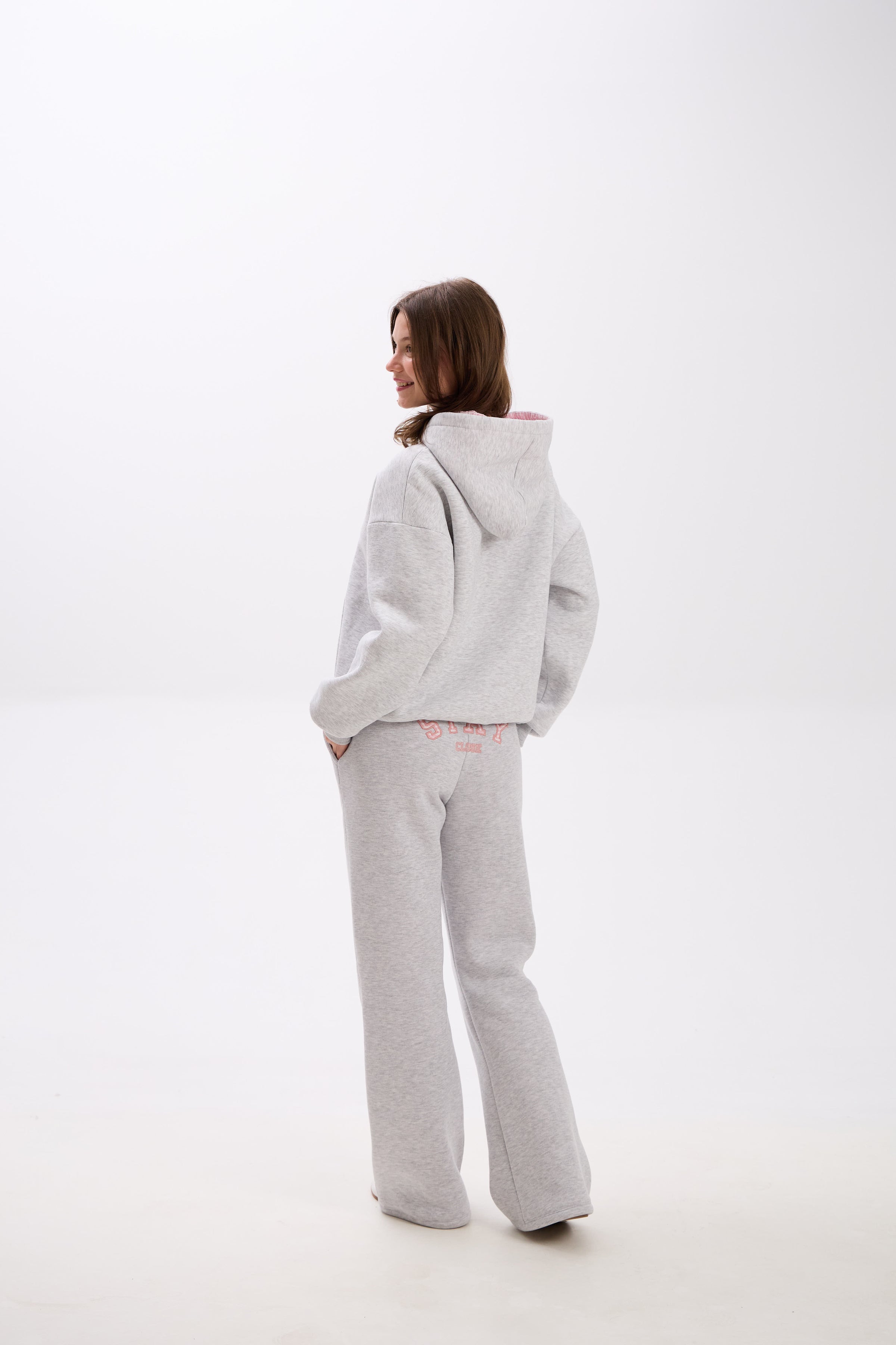 Grey sweatpants with elastic waistband, side pockets, and pink “Stay Close” embroidery on the back.