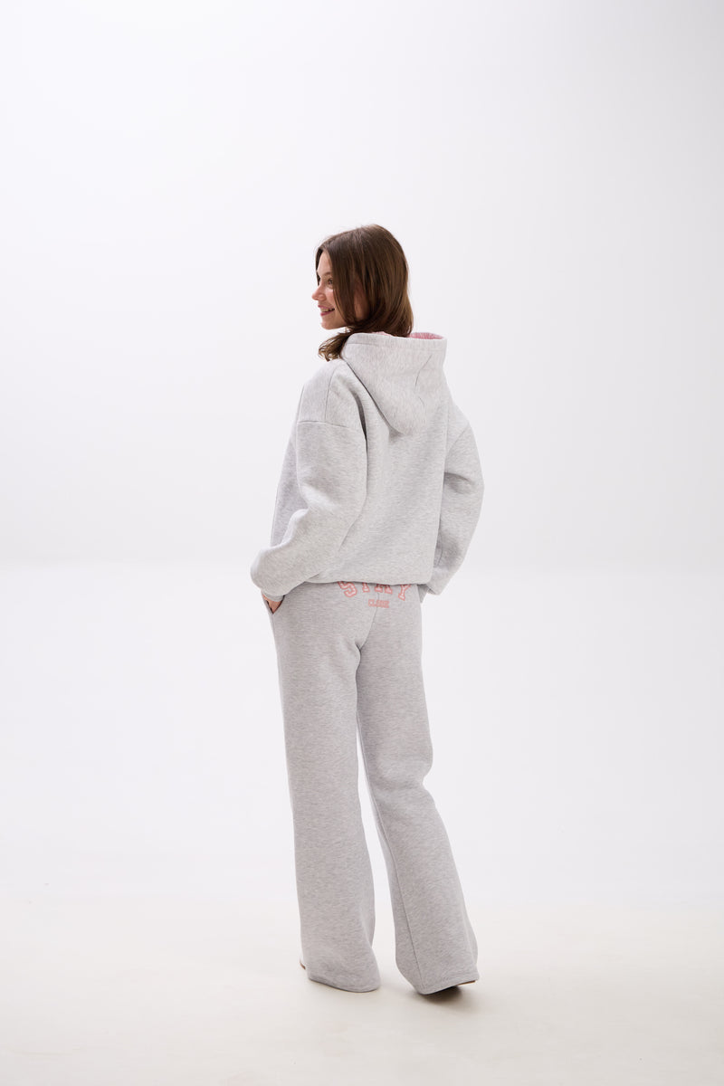 Grey sweatpants with elastic waistband, side pockets, and pink “Stay Close” embroidery on the back.