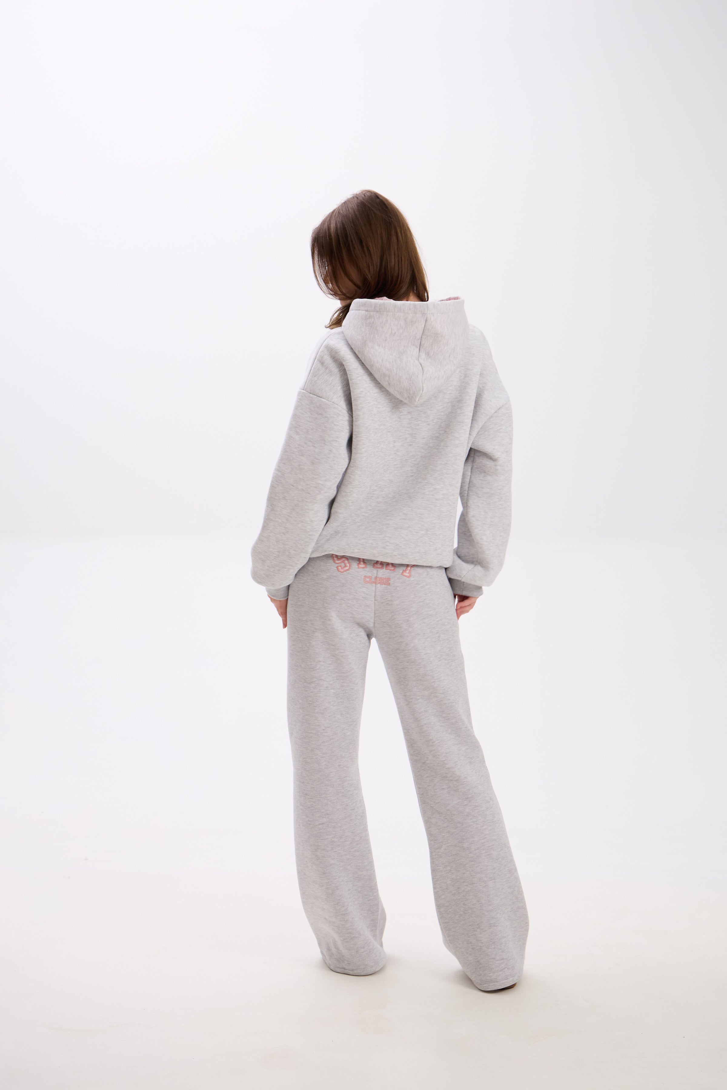 Grey sweatpants with elastic waistband, side pockets, and pink “Stay Close” embroidery on the back.