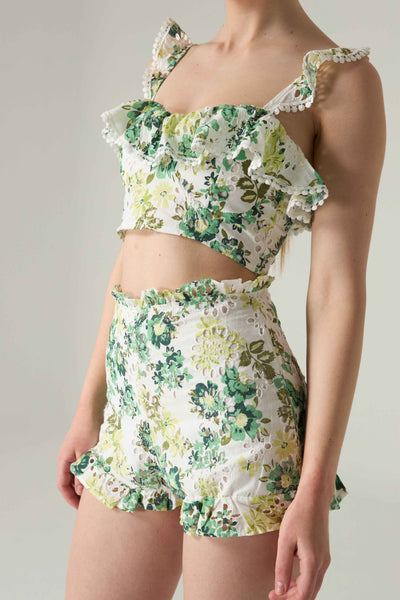 Floral two-piece outfit with ruffled top and shorts on a neutral background.