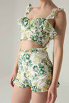 Floral two-piece outfit with ruffled top and shorts on a neutral background.
