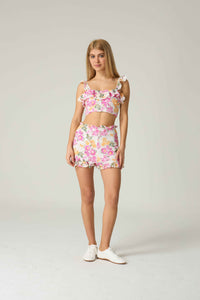 Woman wearing a floral two-piece outfit on a plain background.