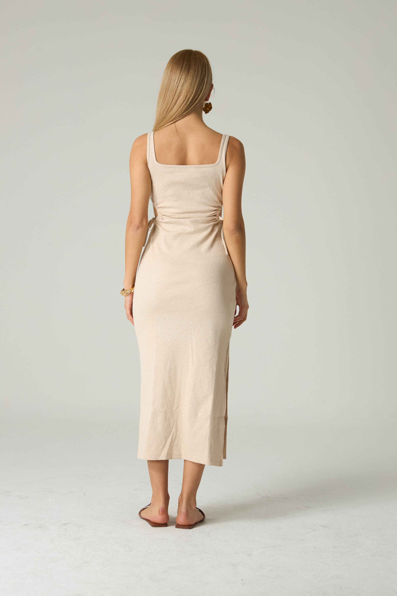 Woman wearing a beige dress with a white background.