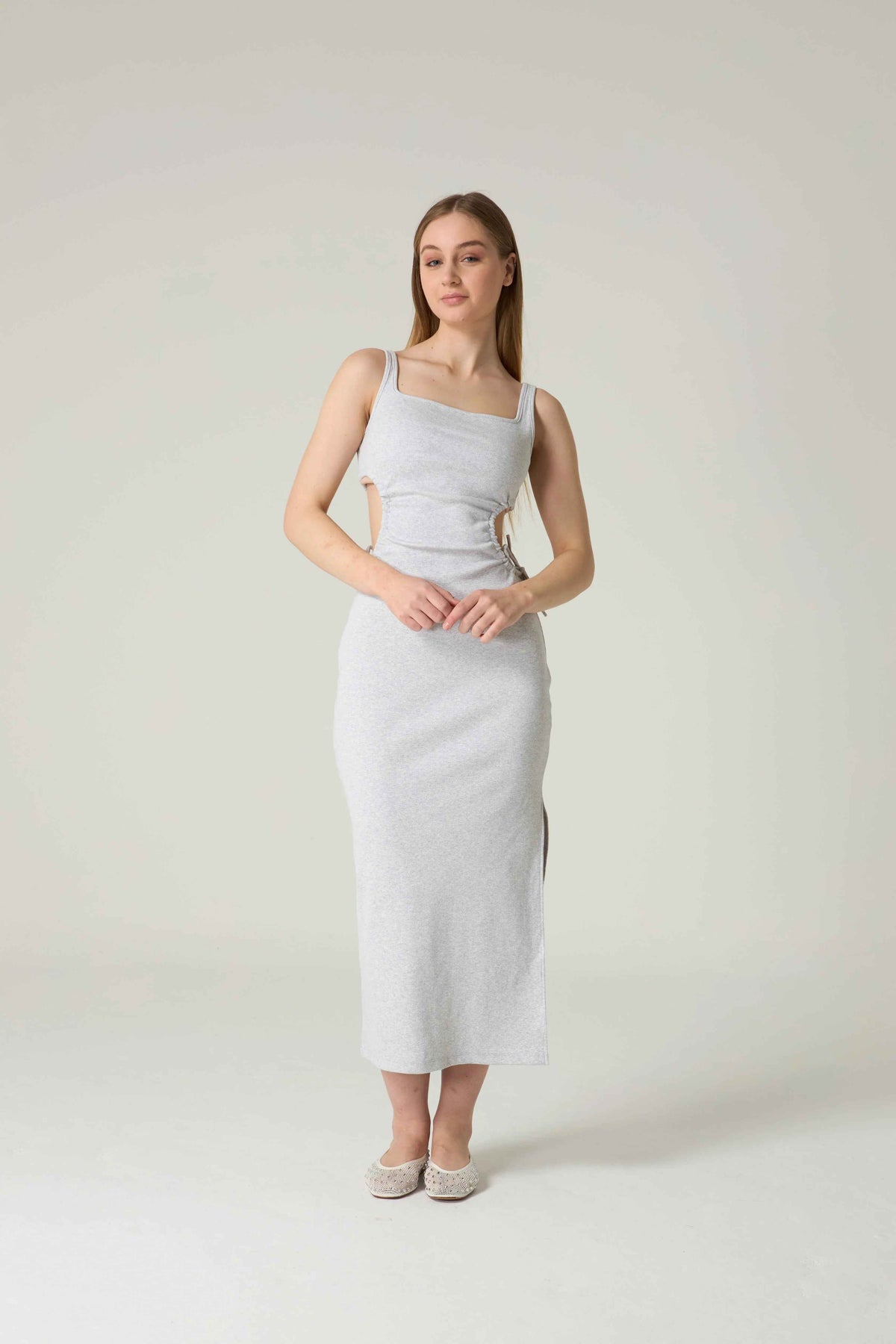 Woman wearing a light gray sleeveless dress against a white background.