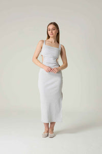 Woman wearing a light gray sleeveless dress against a white background.