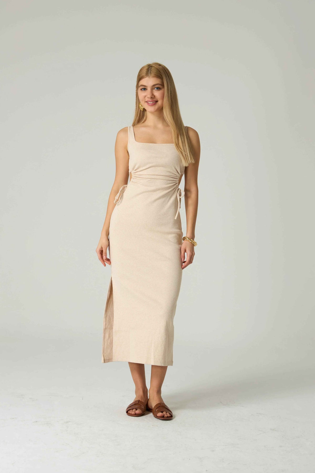 Woman wearing a beige dress against a plain background.