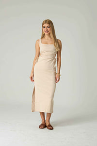 Woman wearing a beige dress against a plain background.