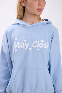 Light blue hoodie with white 'Stay Close' text on a plain background.