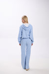 Woman wearing a light blue tracksuit on a white background.