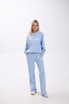 Woman wearing a light blue hoodie and sweatpants set on a white background.