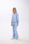 Woman wearing a light blue sweatpants and hoodie on a white background.