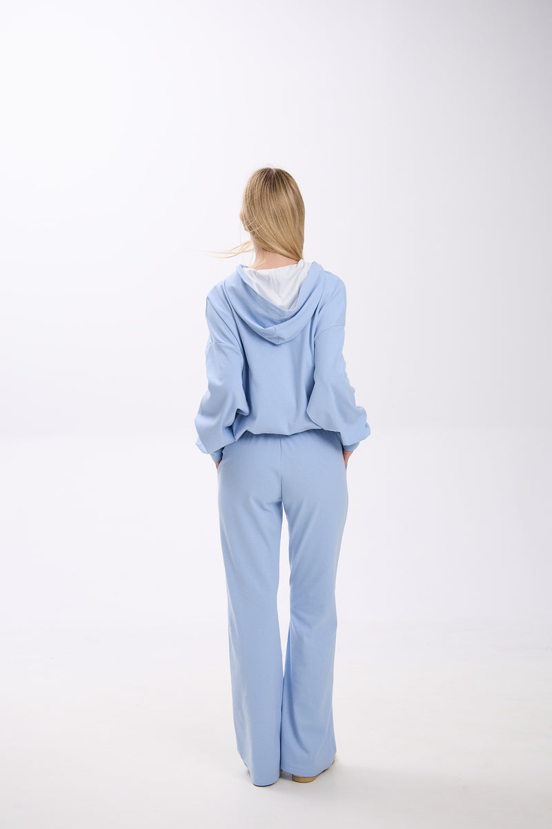 Person wearing a light blue outfit on a white background.