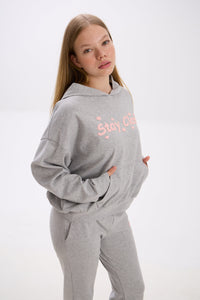 Person wearing a gray hoodie with pink text on a white background.