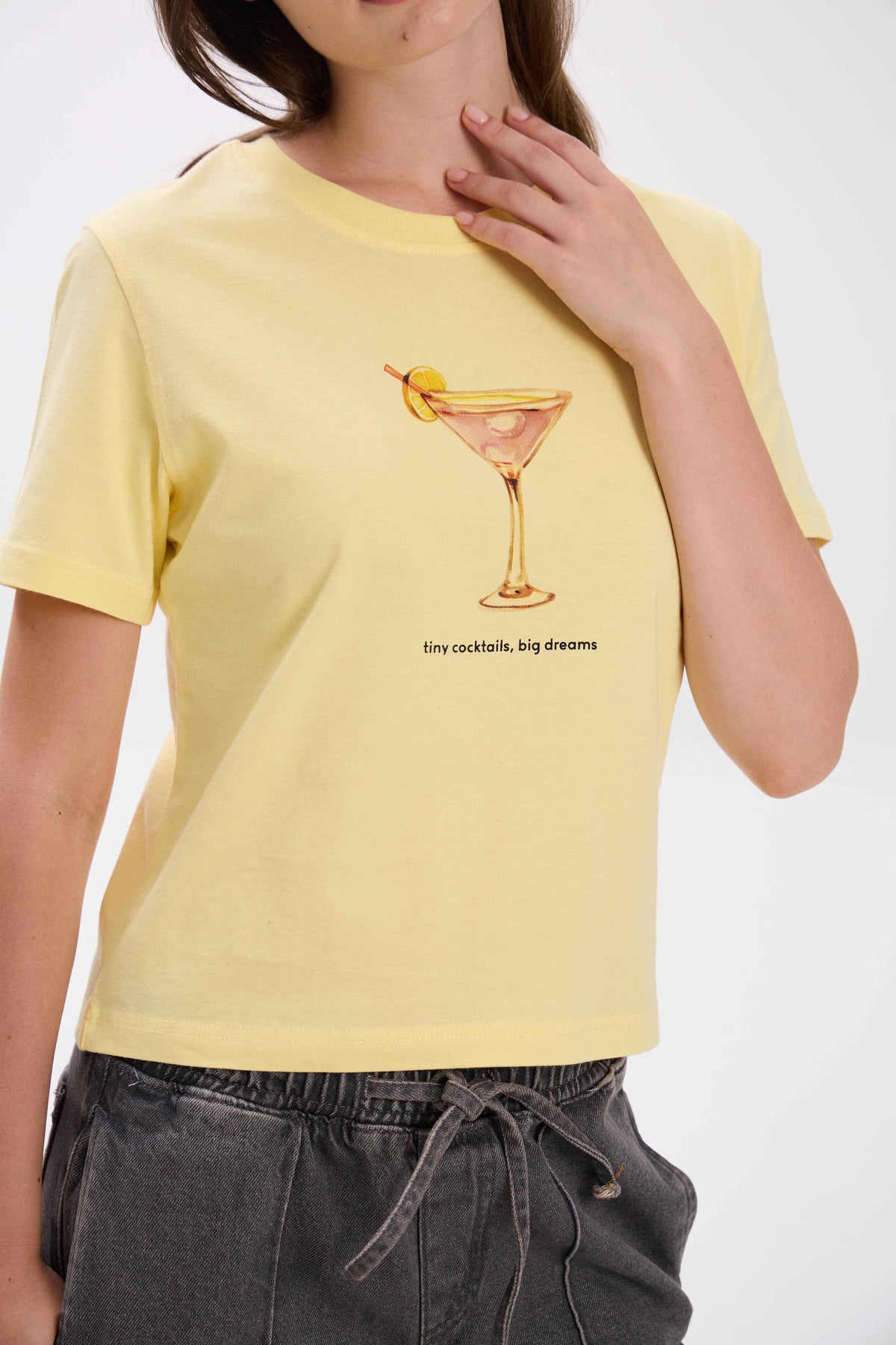 Person wearing a yellow t-shirt with a cocktail graphic and text.