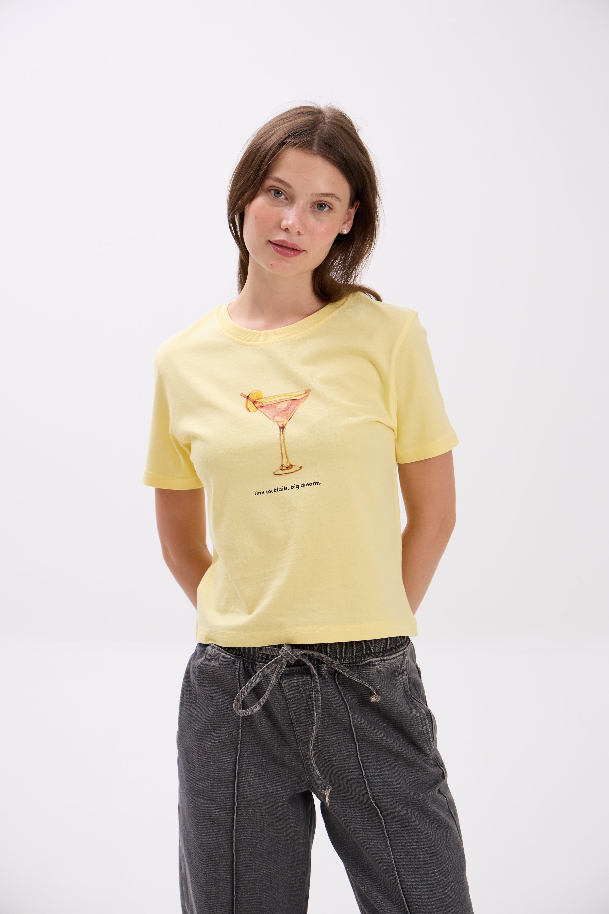 Woman wearing a yellow t-shirt with a graphic design on a white background.
