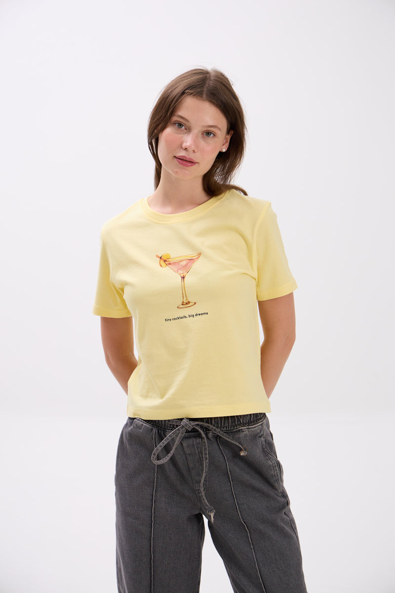 Woman wearing a yellow t-shirt with a graphic design on a white background.