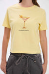 Person wearing a yellow t-shirt with a cocktail graphic and text.