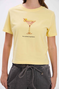 Person wearing a yellow t-shirt with a cocktail graphic and text.